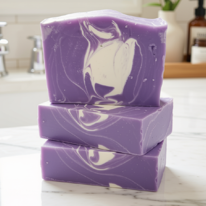 Three stacked rectangular bars of lavender purple soap with white marbled swirls, set on a light marble countertop in a softly blurred bathroom setting.