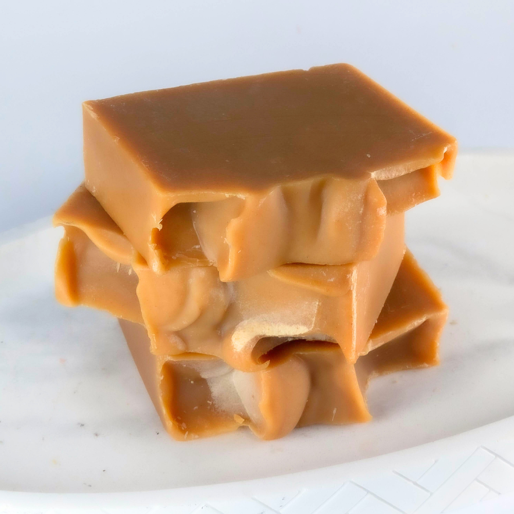 Stack of caramel-colored soap bars on a white surface
